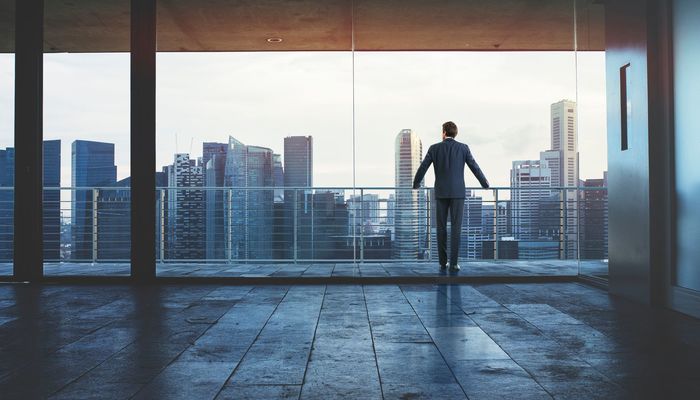 Businessman stood on the balcony of a tall building looking out over the city