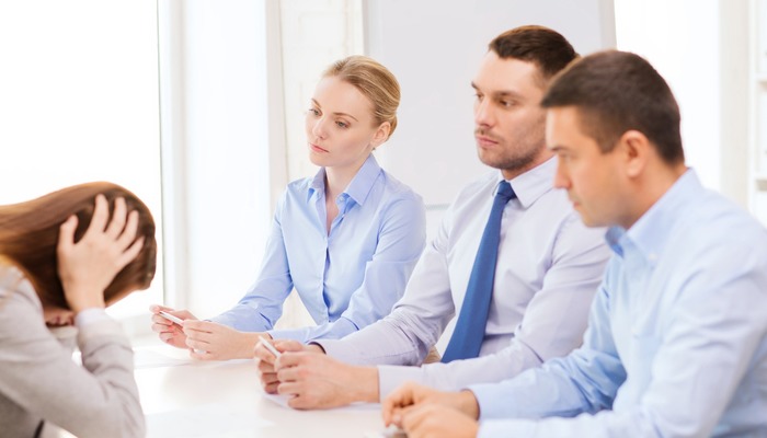 A woman getting fired by three of her superiors