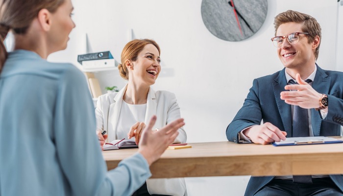 Three happy employees laughing together during a discussion