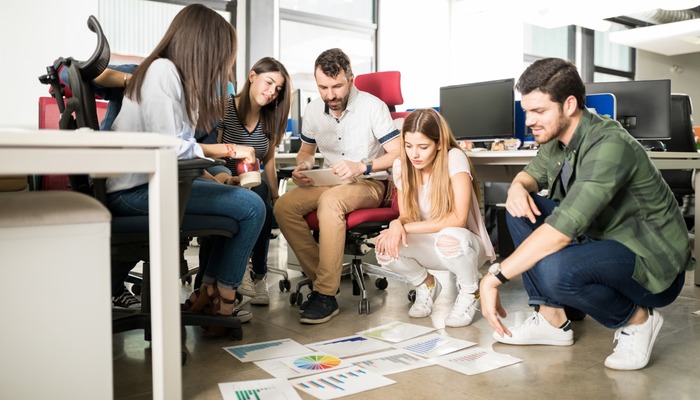 Group of employees at a trendy startup looking at an assortment of graphs and charts