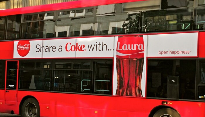Coca-Cola's 'Share a Coke' campaign ad on the side of a bus in the UK