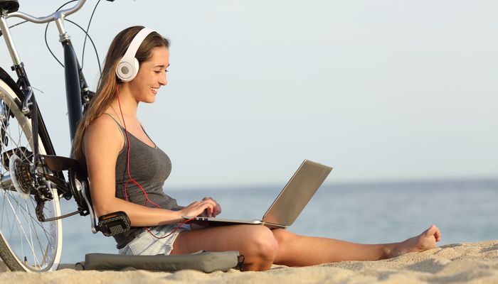 Teen girl studying with a laptop on the beach