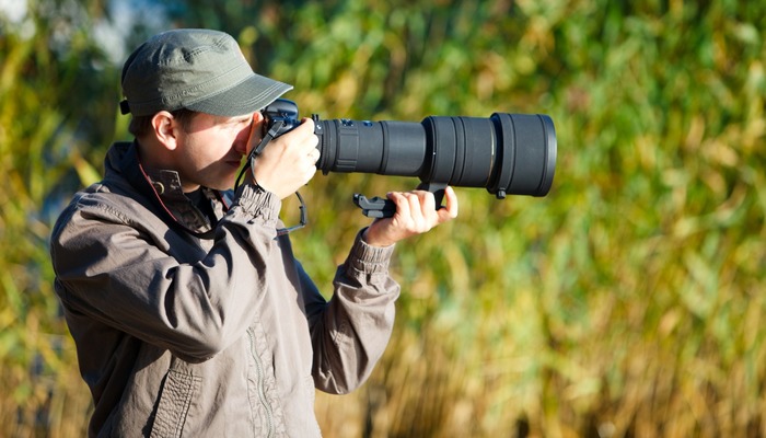 Nature photographer taking a picture and adjusting lenses
