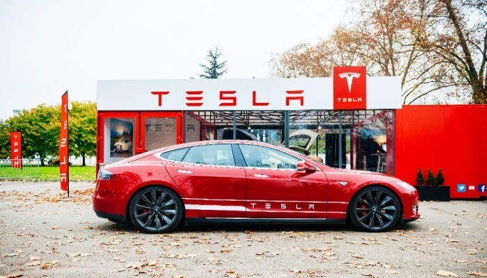 Red Tesla car parked in front of a Tesla showroom