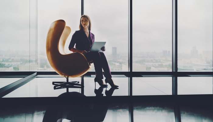 Young business woman sitting in a curved armchair in a skyscraper office